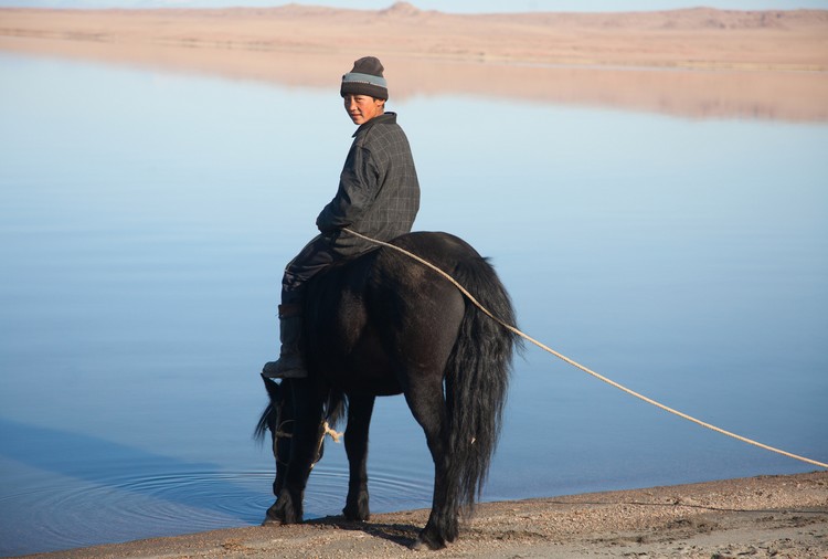 Jeune mongol et son cheval au lac, Mongolie